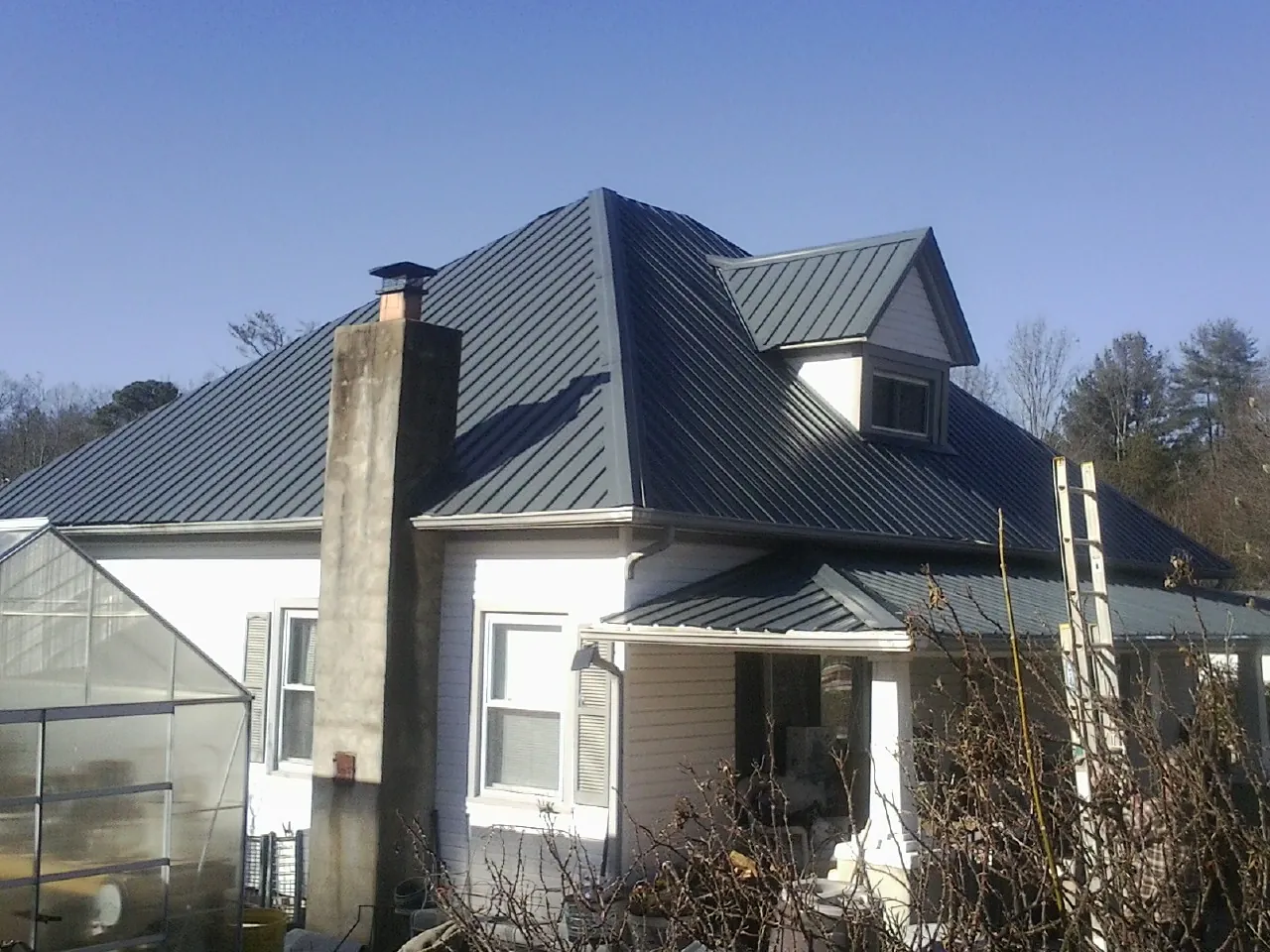 Dark blue standing seam metal roof on a white farmhouse with dormer — Slate & Tile Roof Repair by Roofing Brothers in Henefer