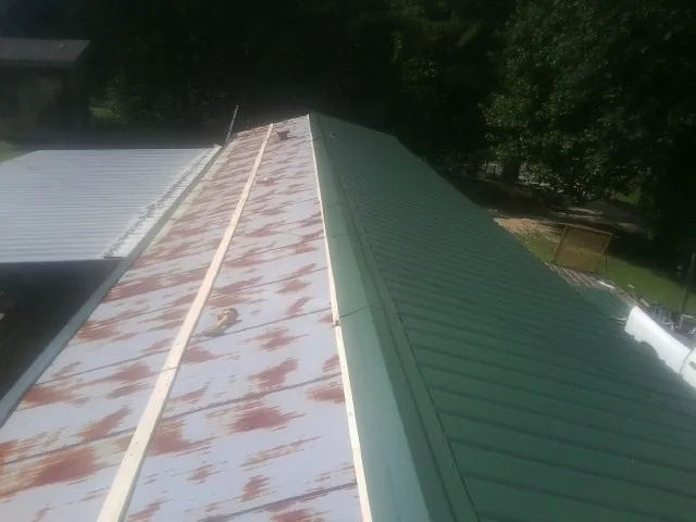 Old rusted panels beside newly installed green metal roofing — Wind Damage Roof Repair by Roofing Brothers in Henefer