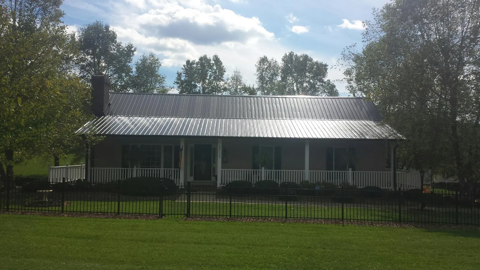 Gray metal roof on a brick ranch with a full width front porch — Gutter Guard Installation work by our crew in Henefer